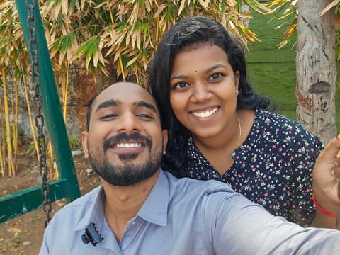 Hari and Sneha beaming on a park swing under bamboo